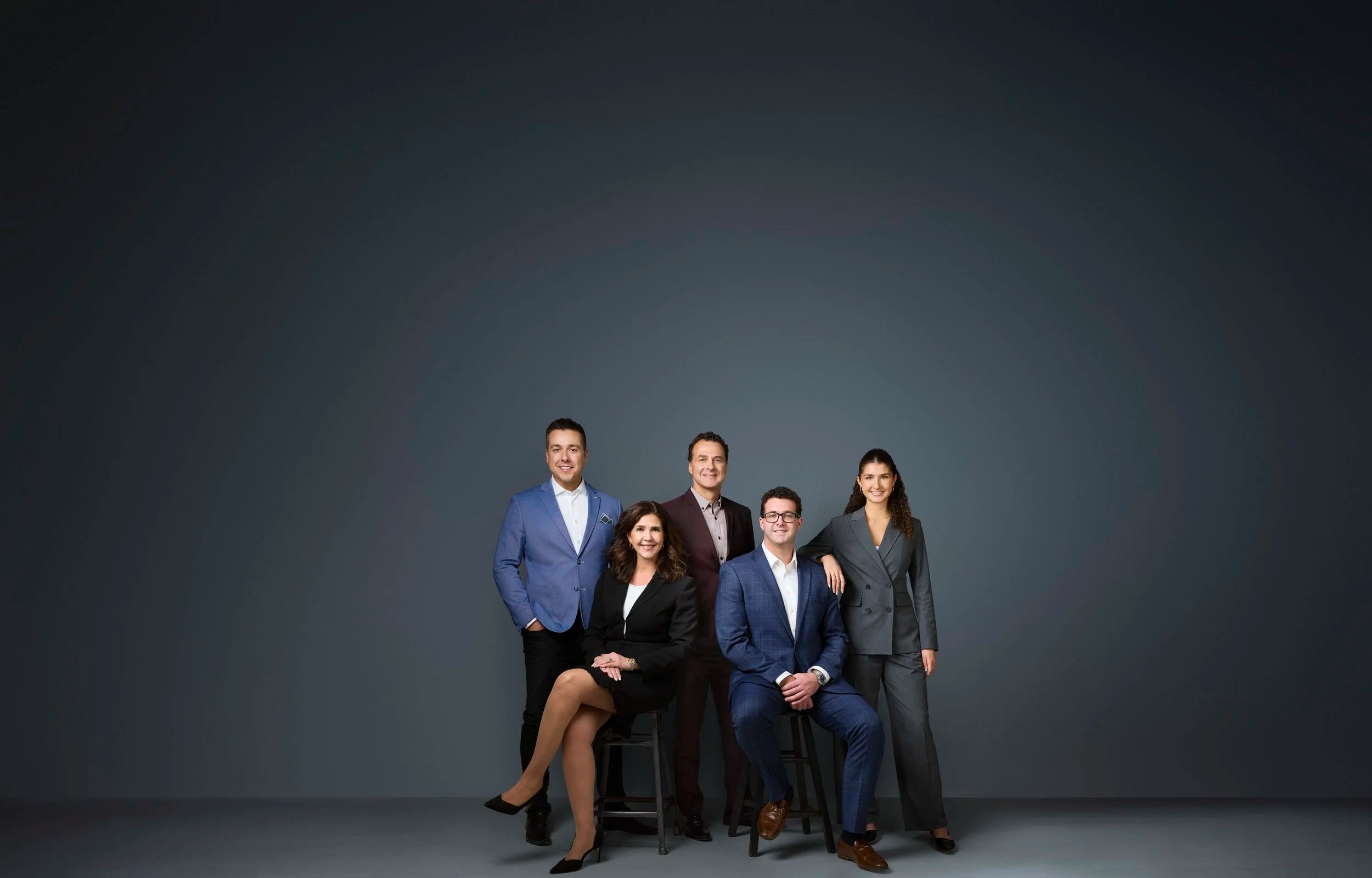 Group photo of a five-person team, seated and standing, Edmonton studio