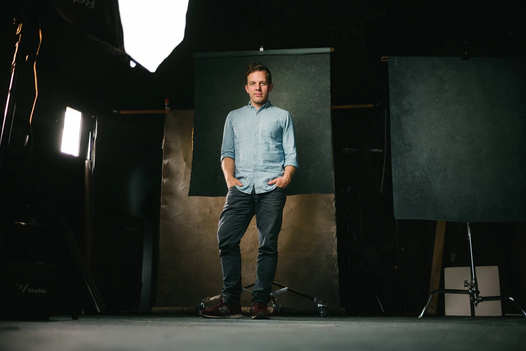 Portrait of a man standing in a photography studio in Edmonton with studio lights and backdrop.