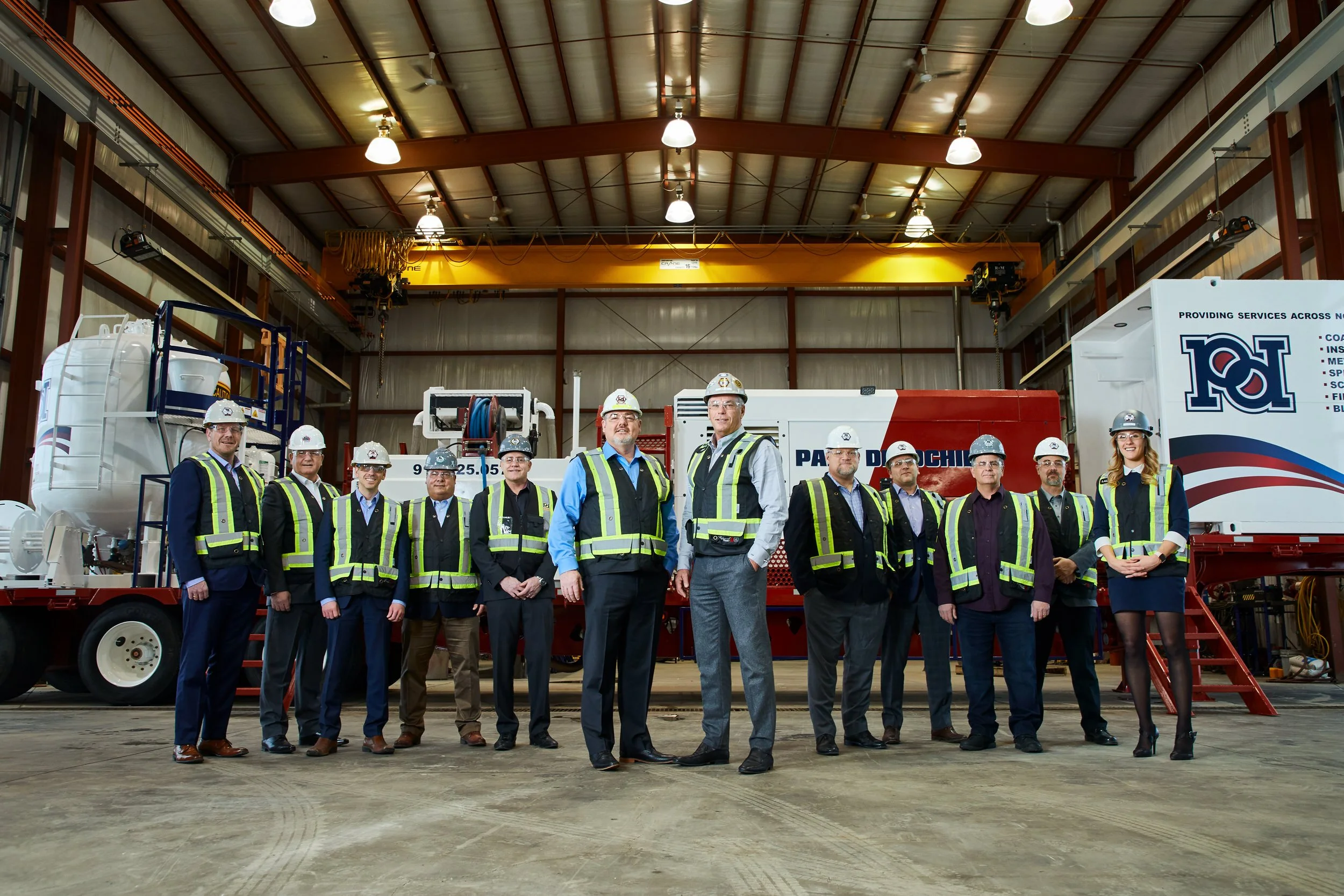 Group photo of a crew in safety vests and hard hats in their own shop, Edmonton