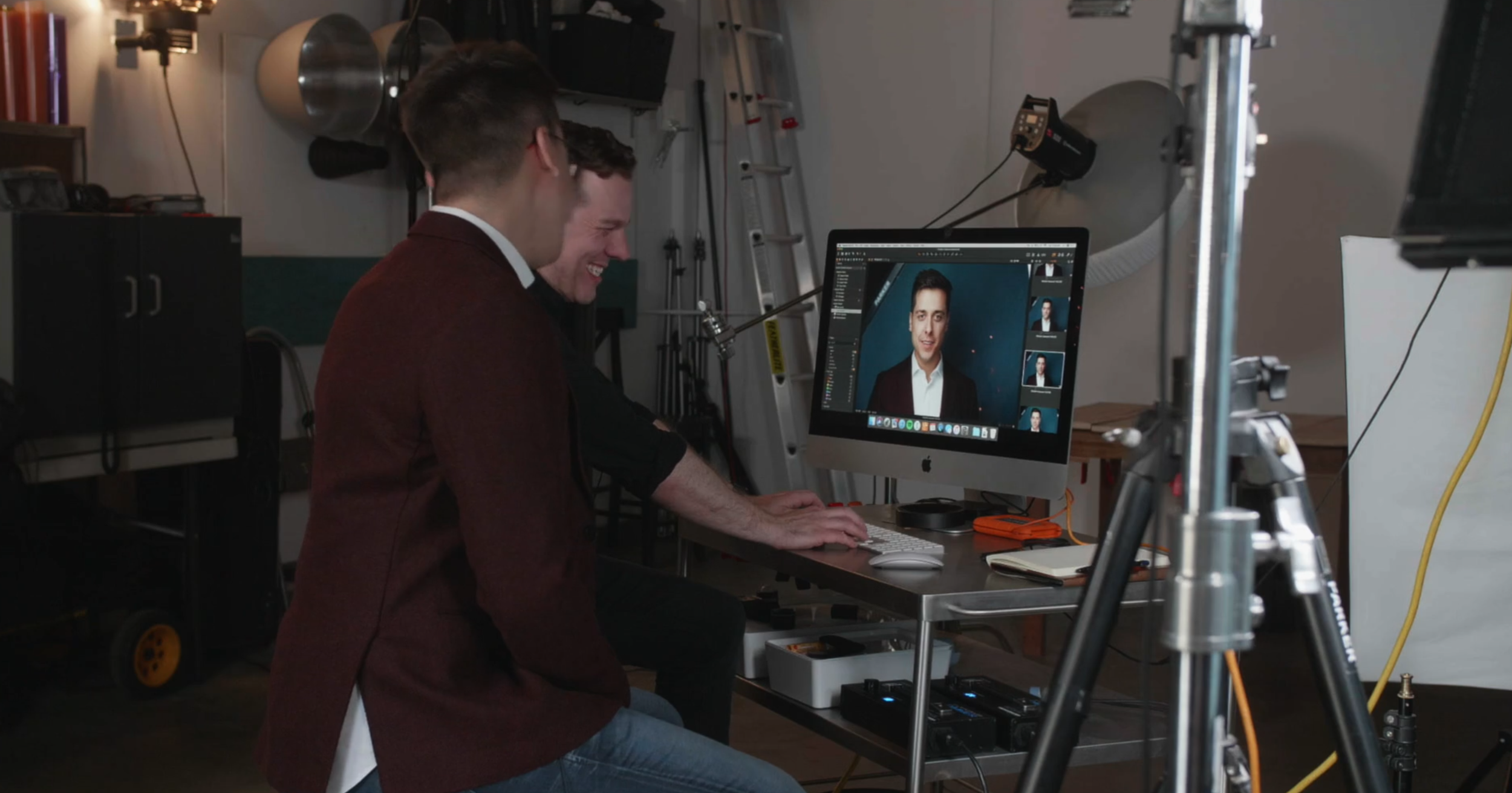 Two men working in a photography studio in Edmonton, Alberta. One using a computer, with camera equipment and lighting in the background.