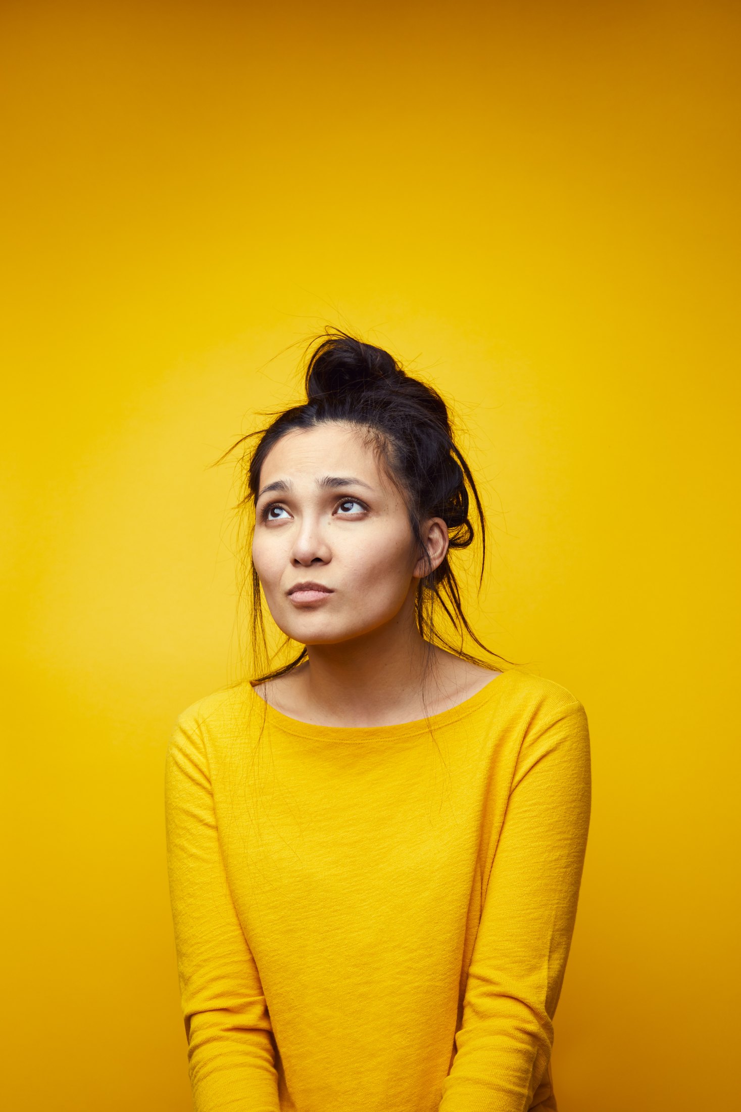 A performer in a yellow sweater against yellow, looking up out of frame