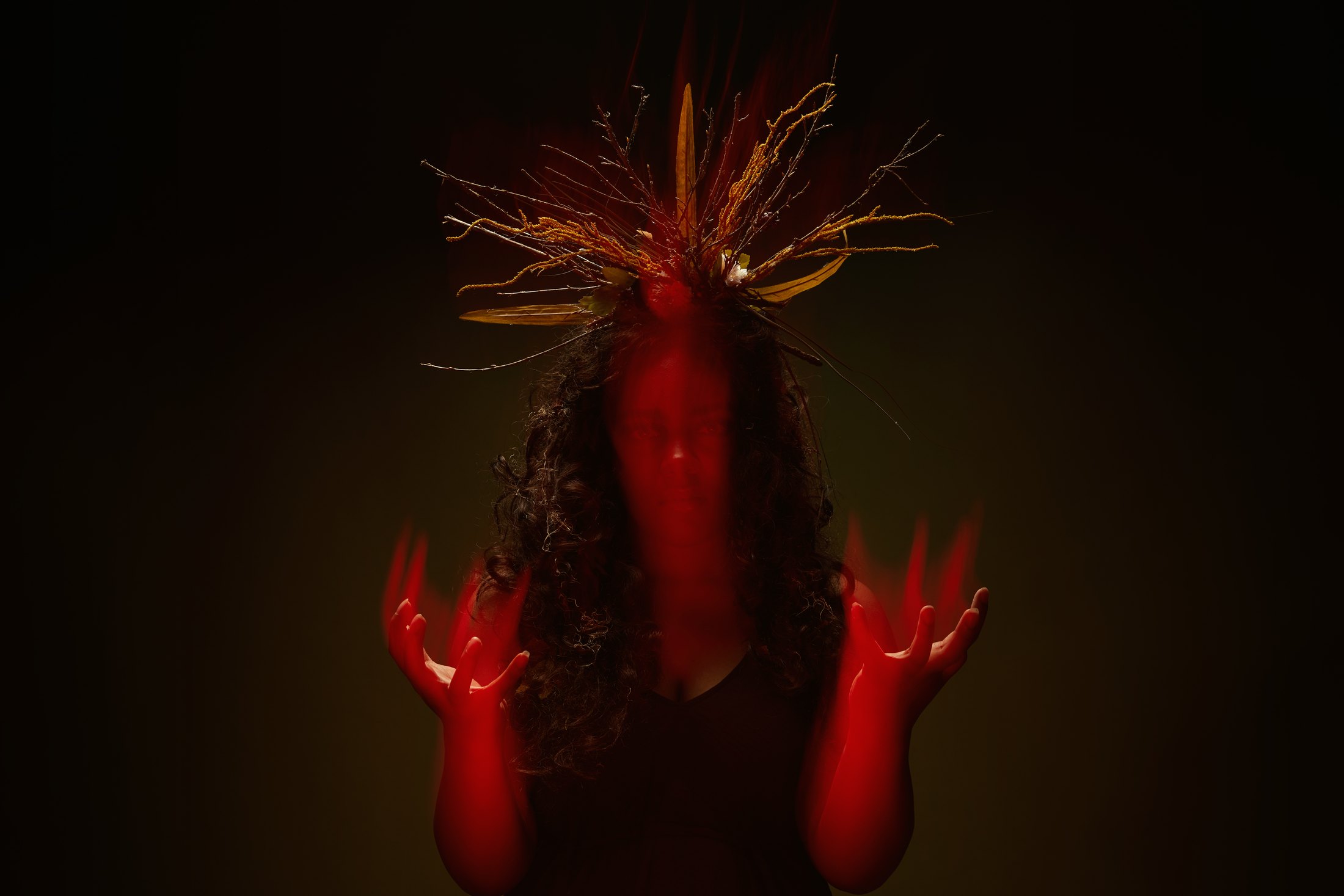 Macbeth promo, a multiple exposure in red light: both hands raised, hair lifting above them