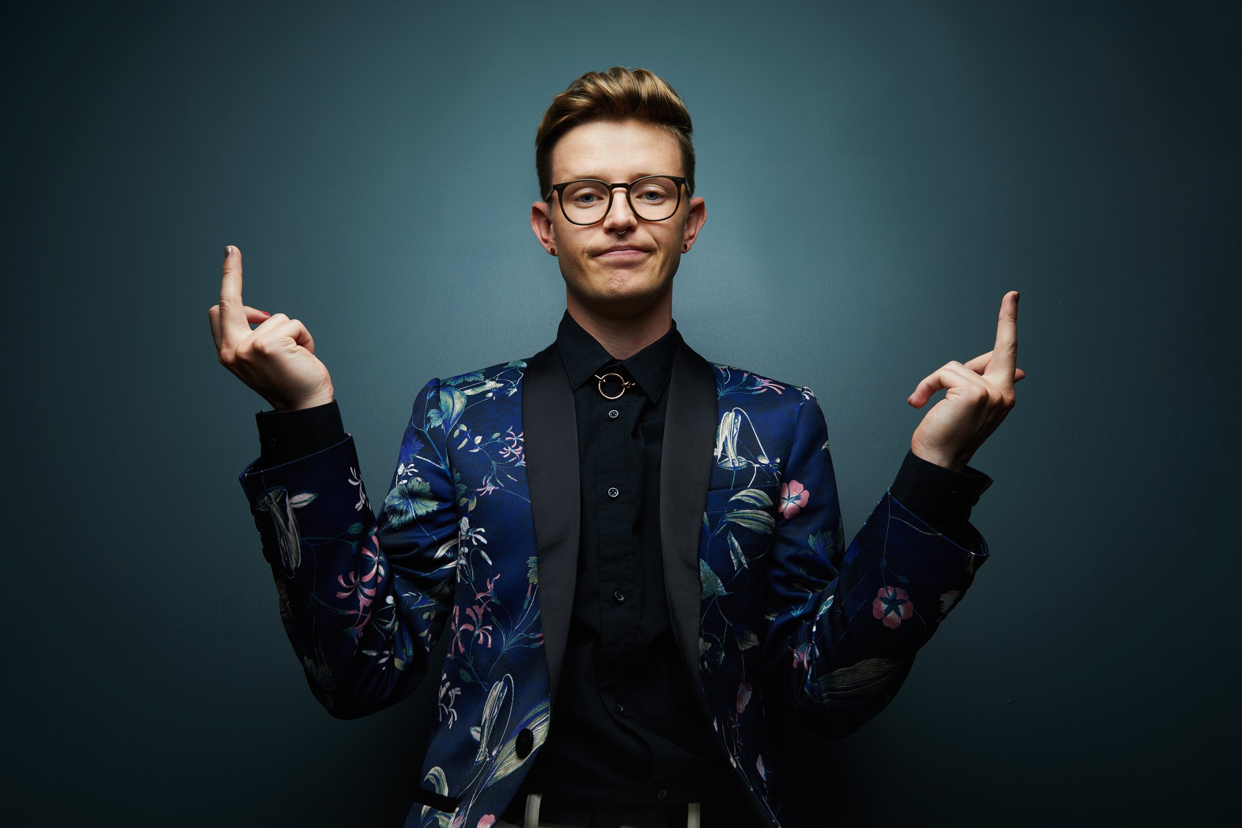 The same session, both index fingers up and a shrug of a smile