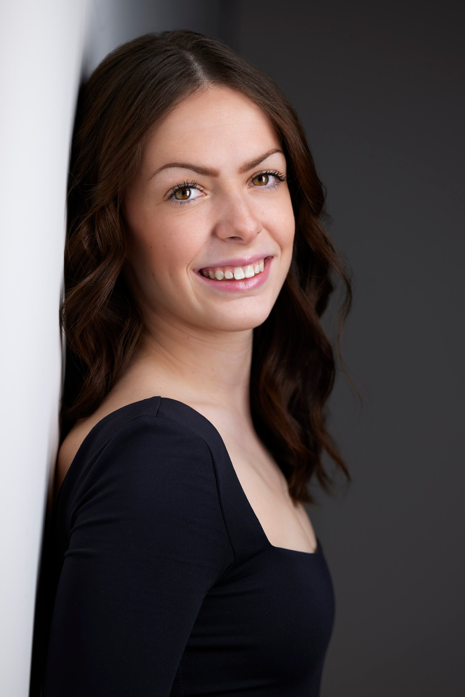 Dance headshot: a black top against black, standing