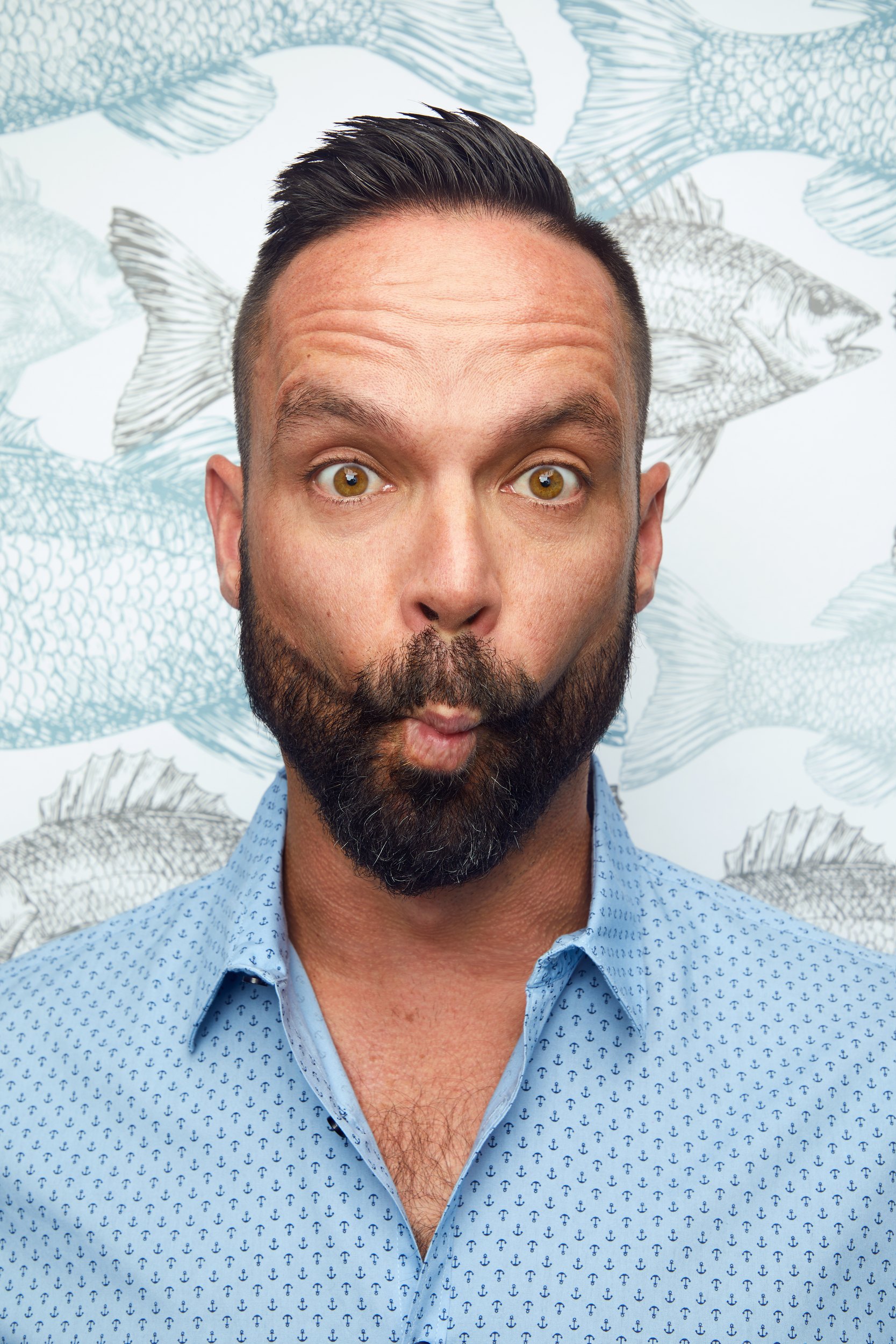 Rob Tryon, eyes wide and lips pursed, against a fish-print wallpaper