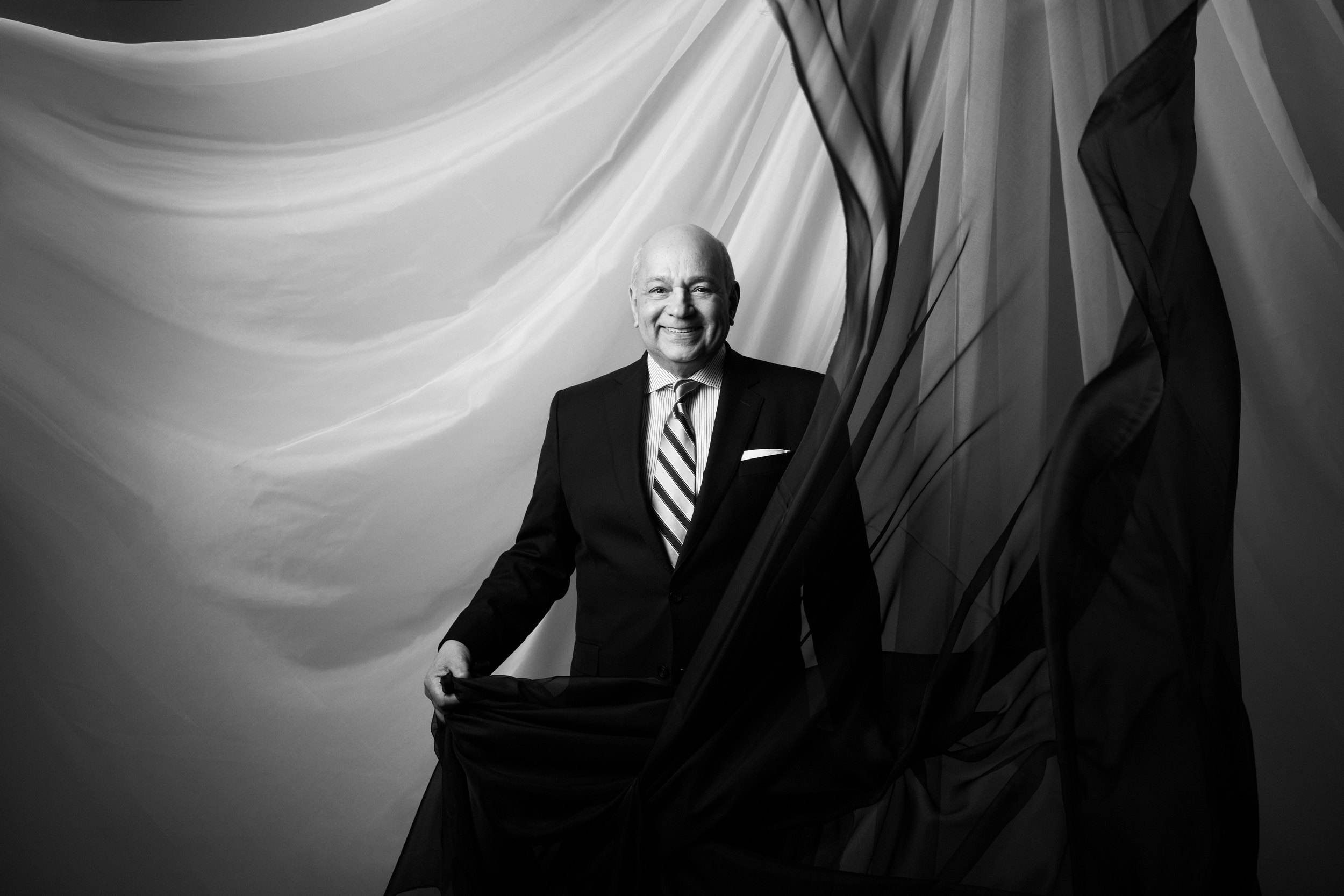 Black and white: a man holding the cloth wide, caught mid fall
