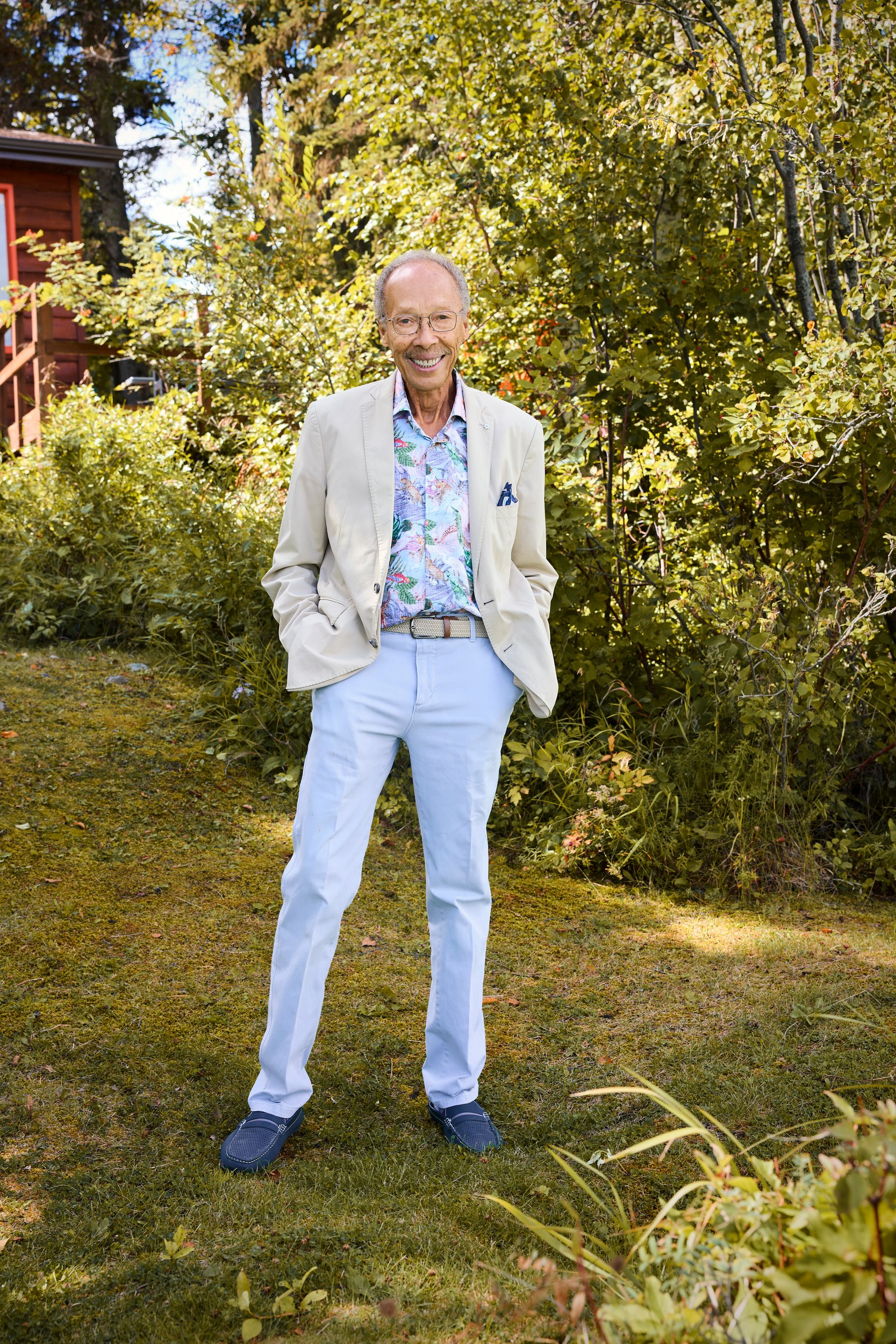 Dr. Anthony Fields standing on the grass in his garden, in a pale suit