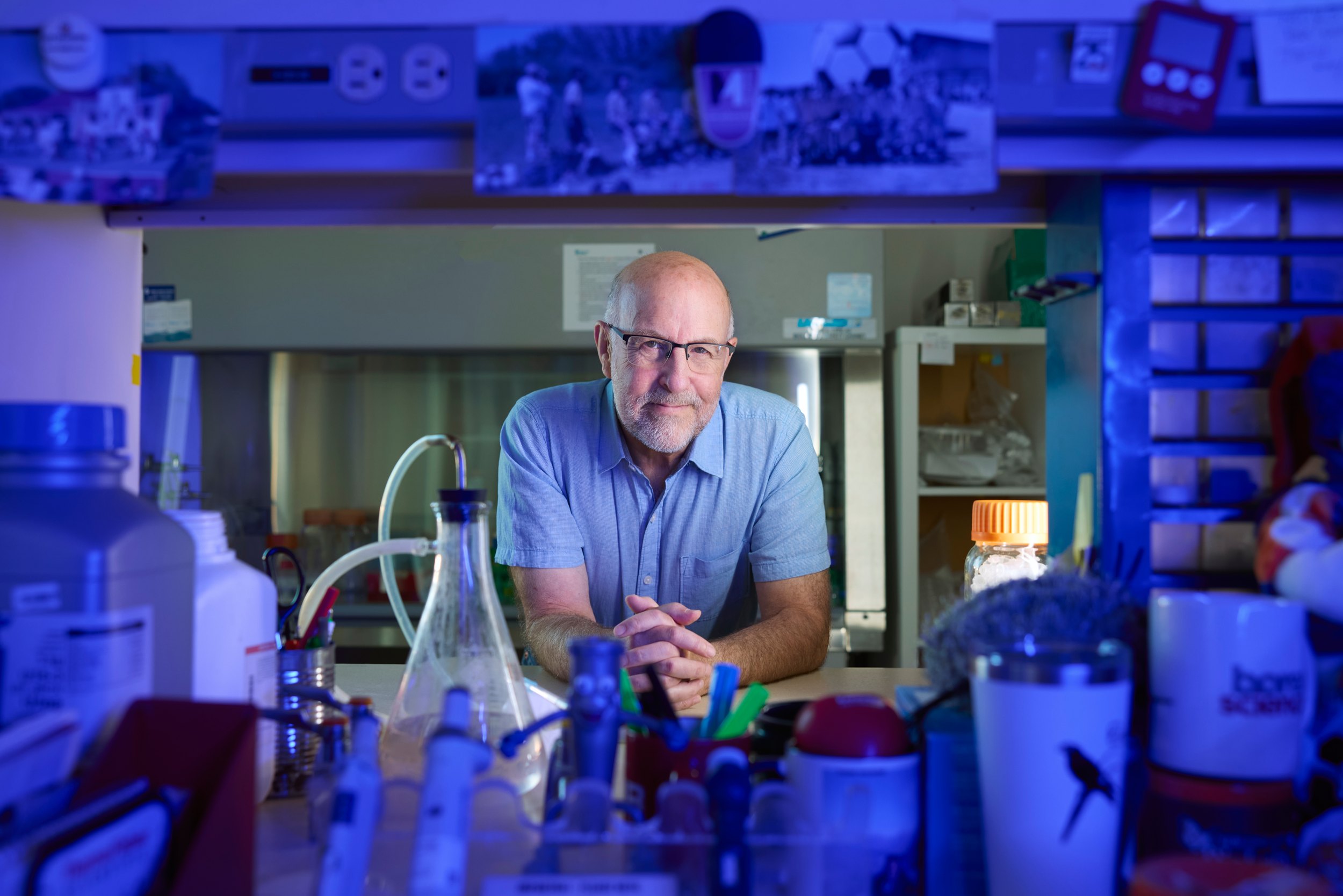 Dr. Michael Weinfeld at his lab bench, lit blue, the glassware in front of him