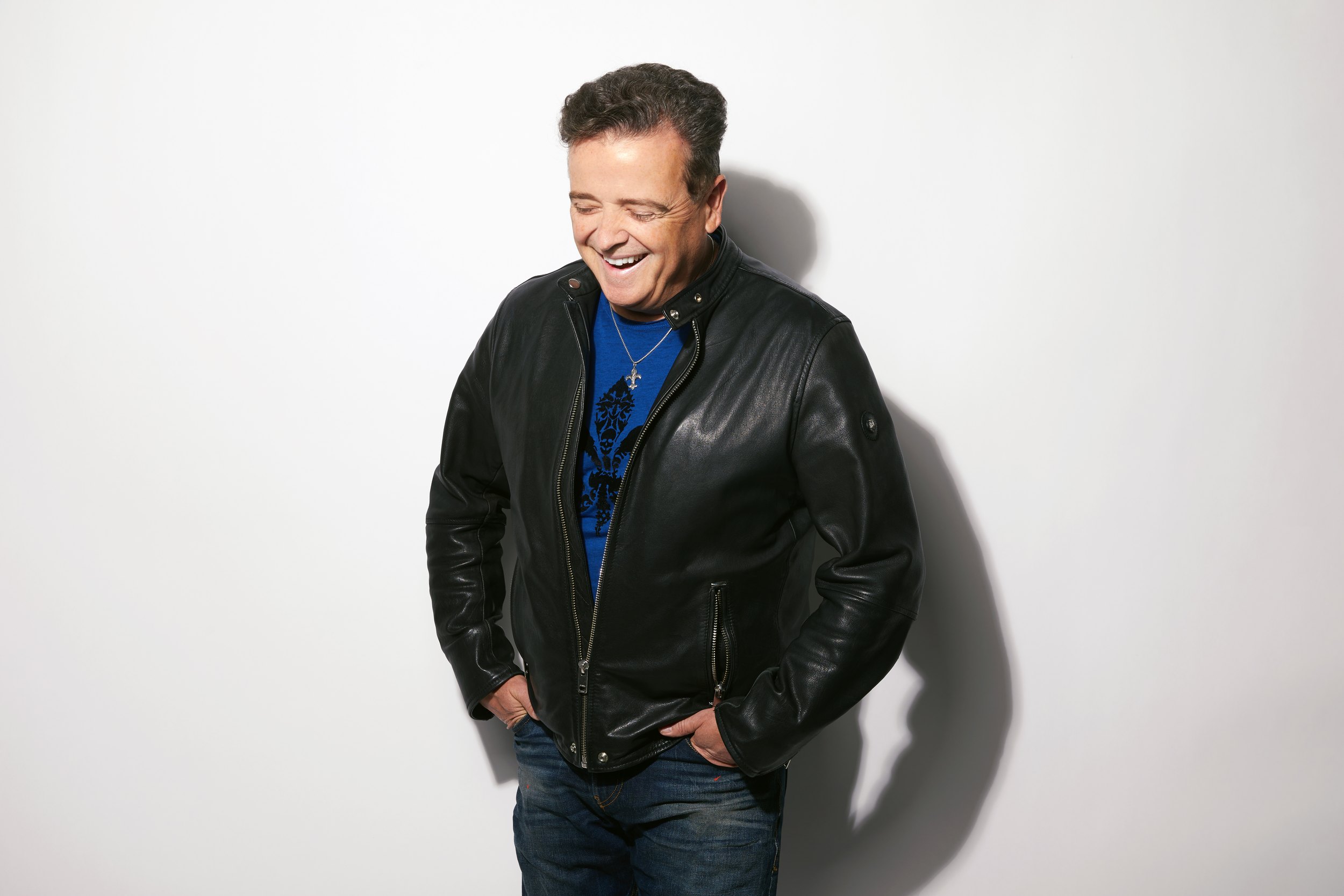 Dr. Luc Berthiaume in a black leather jacket, laughing, his shadow on the white wall behind