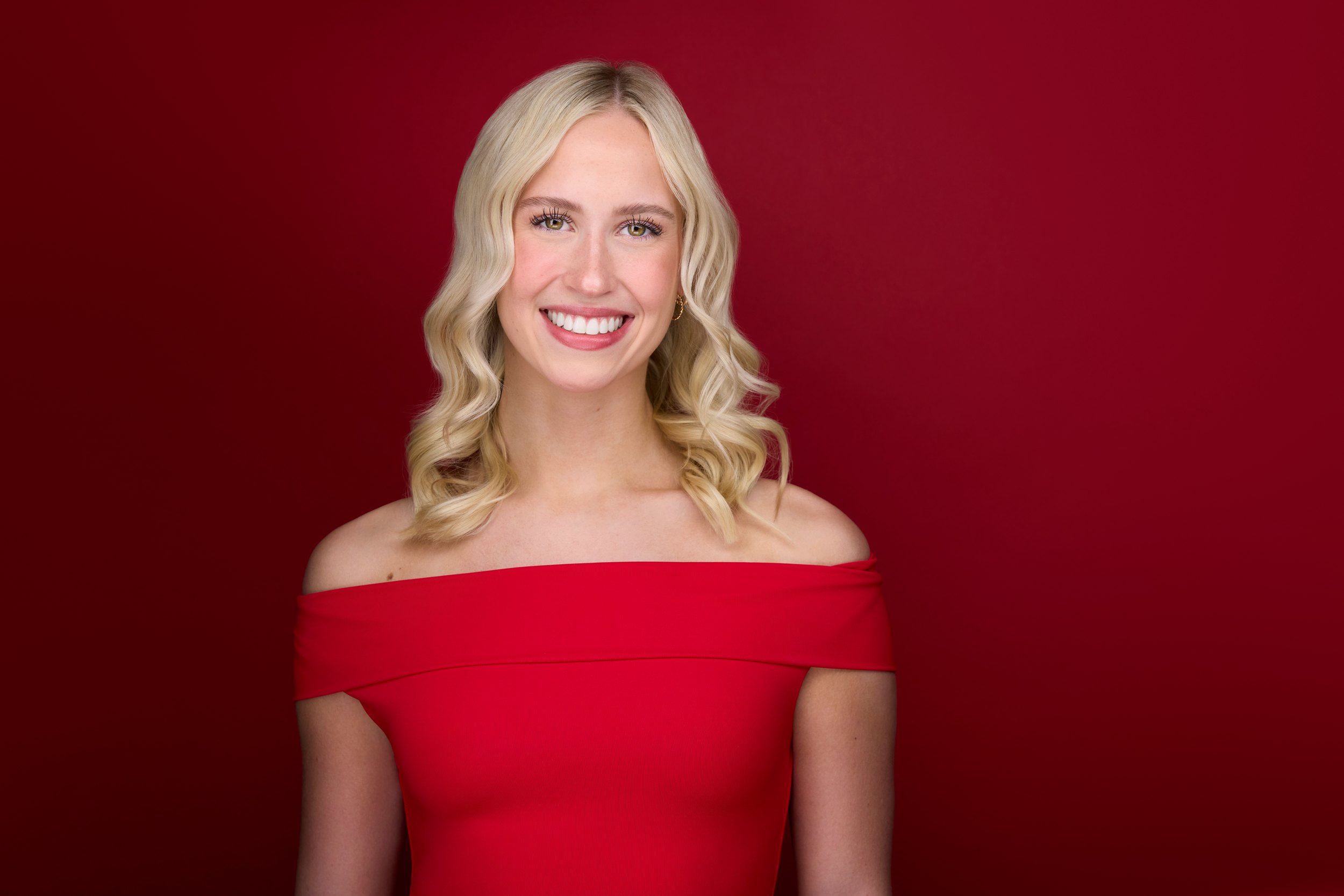 Dance headshot: a dancer in a red off-the-shoulder top against a red backdrop, Edmonton studio