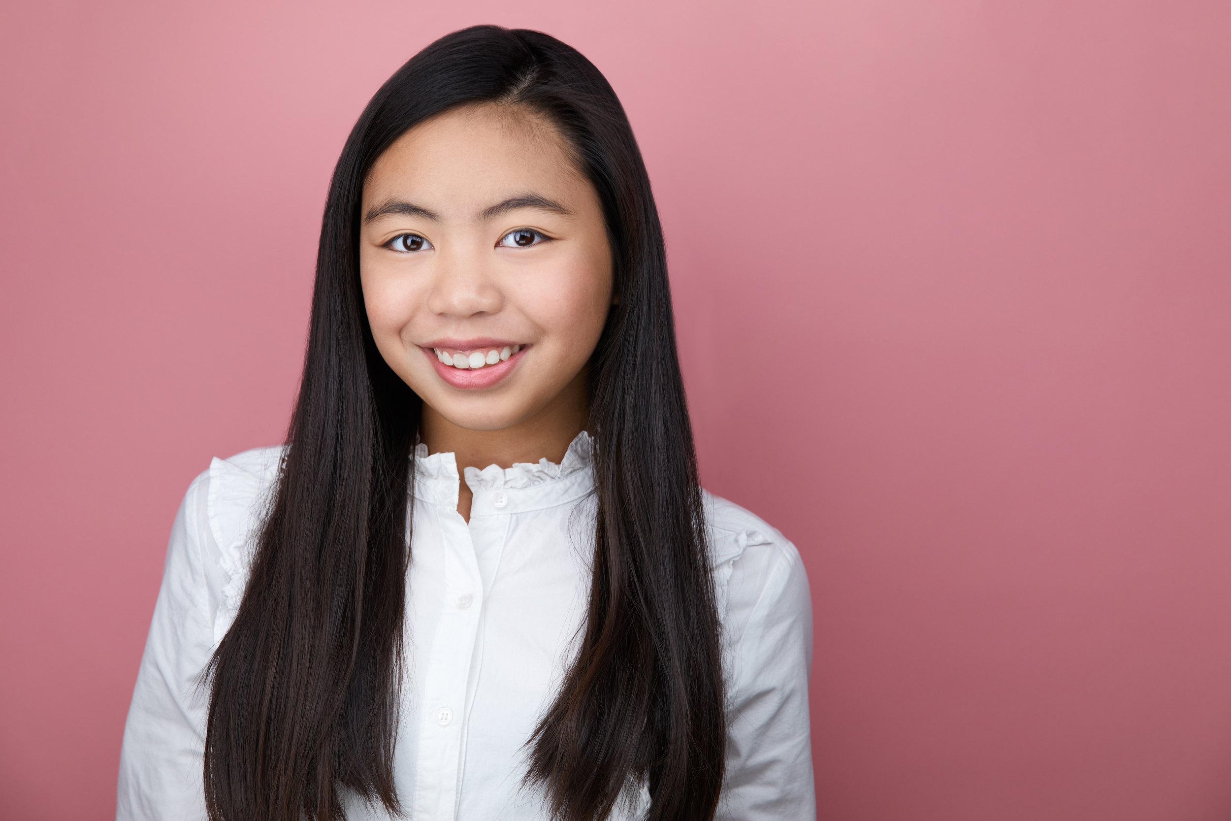 Kids and teens headshot: a white blouse against pink, long dark hair