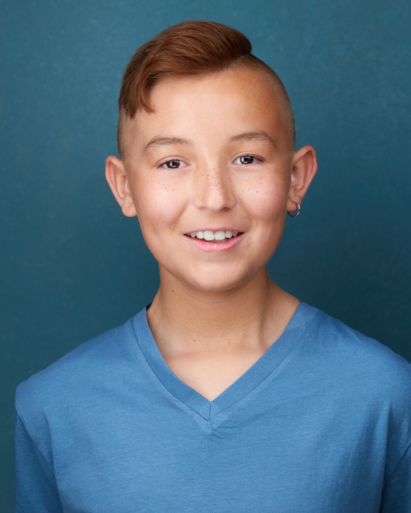 Kids and teens headshot: a blue V-neck against teal, smiling