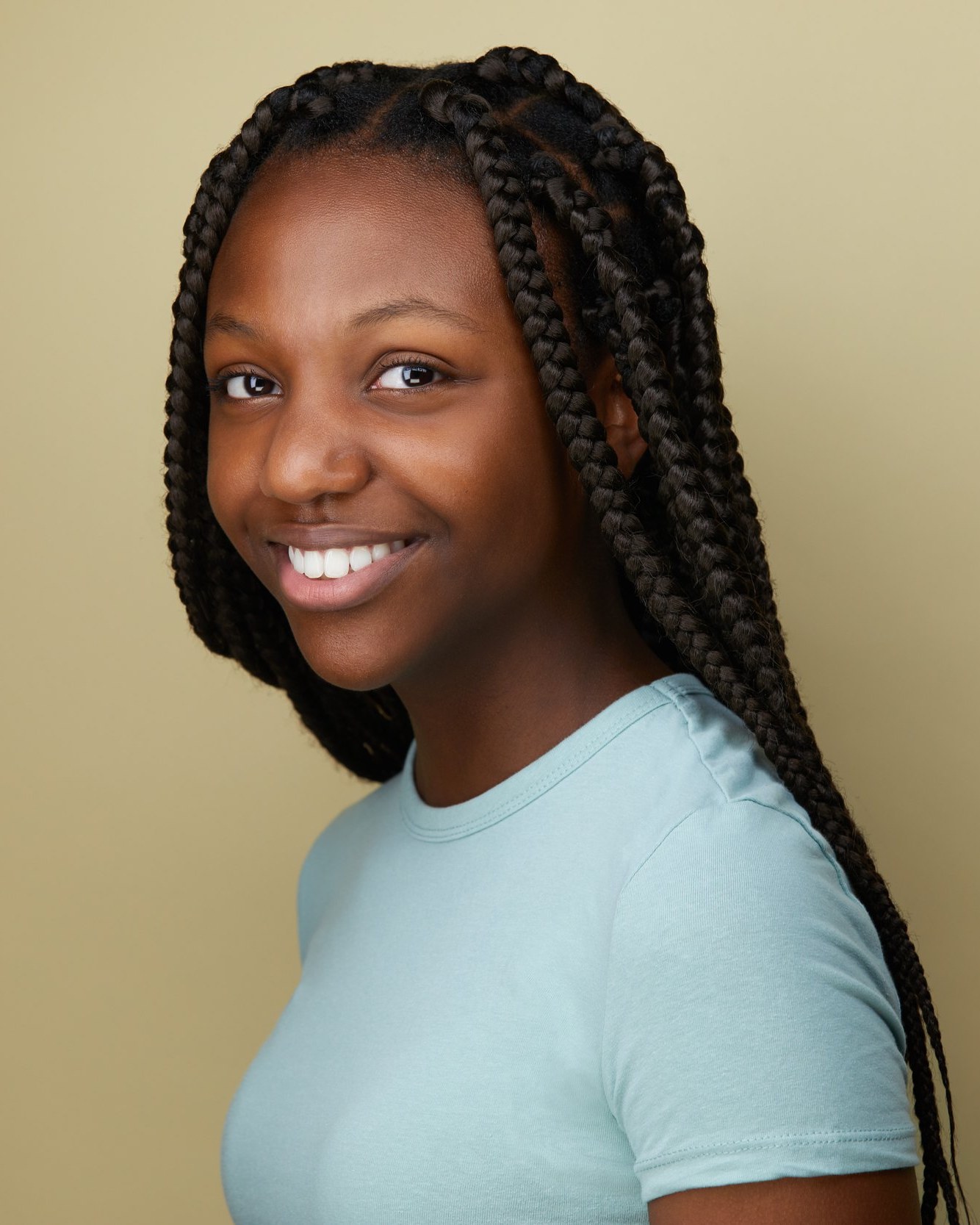 Kids and teens headshot: a mint tee against cream, braids, smiling