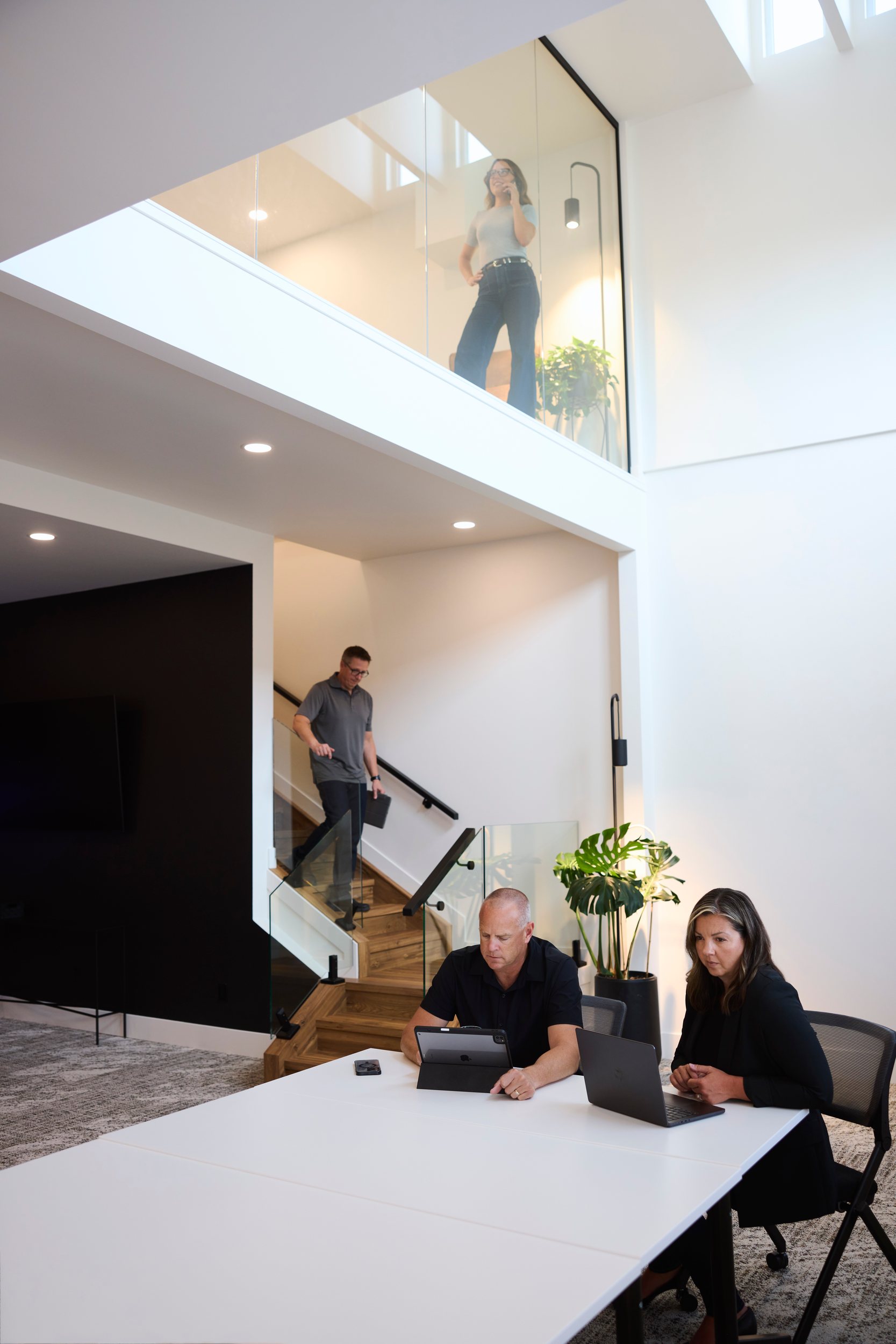 The team at work in their two-storey office, one agent on the glass mezzanine above