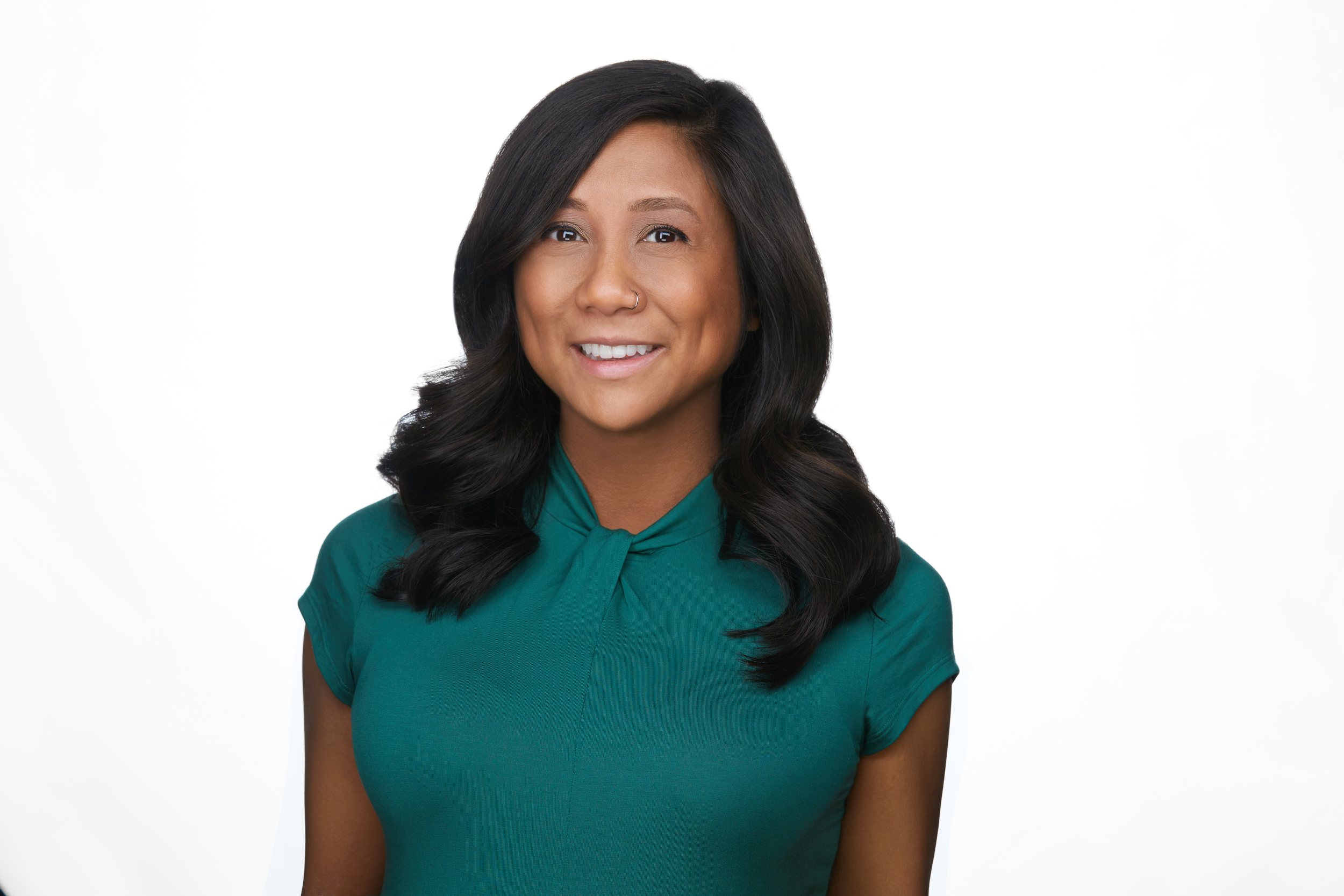 Real estate headshot: long dark hair, a green top, on white