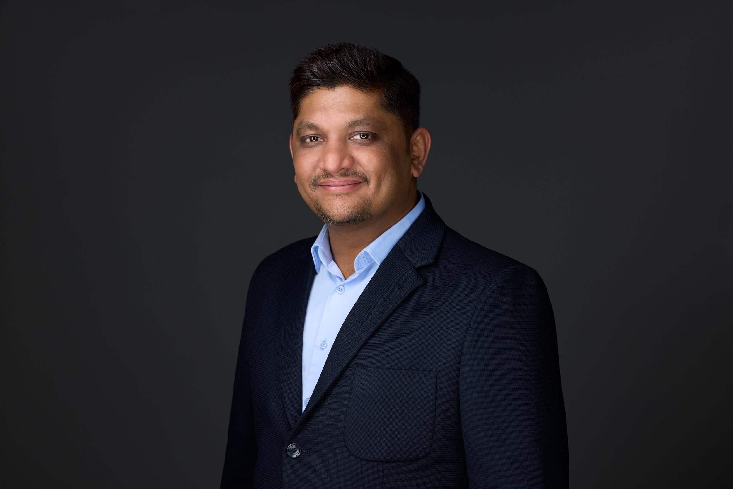 Real estate headshot: a navy blazer over a light blue collar, on dark