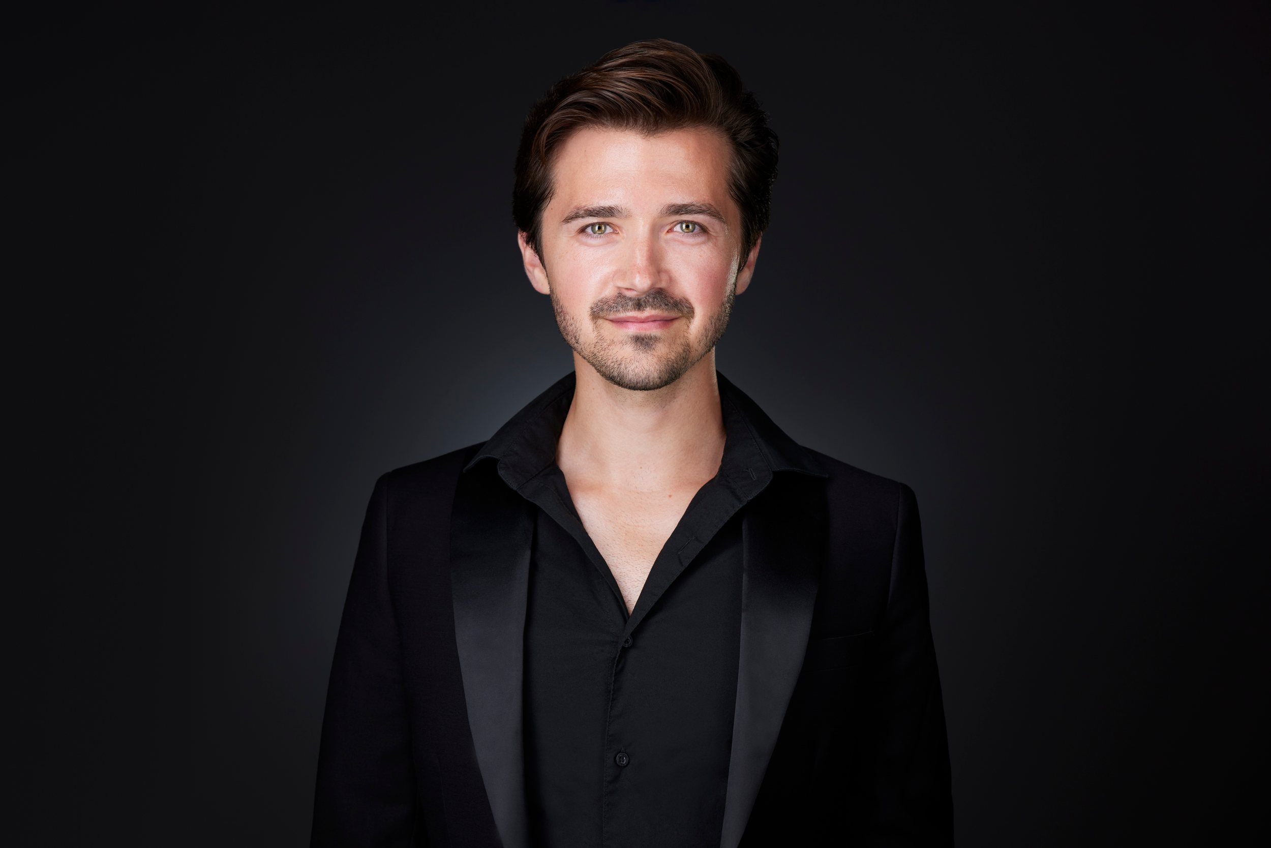 Real estate headshot: a black suit and a black shirt with a satin lapel, on dark