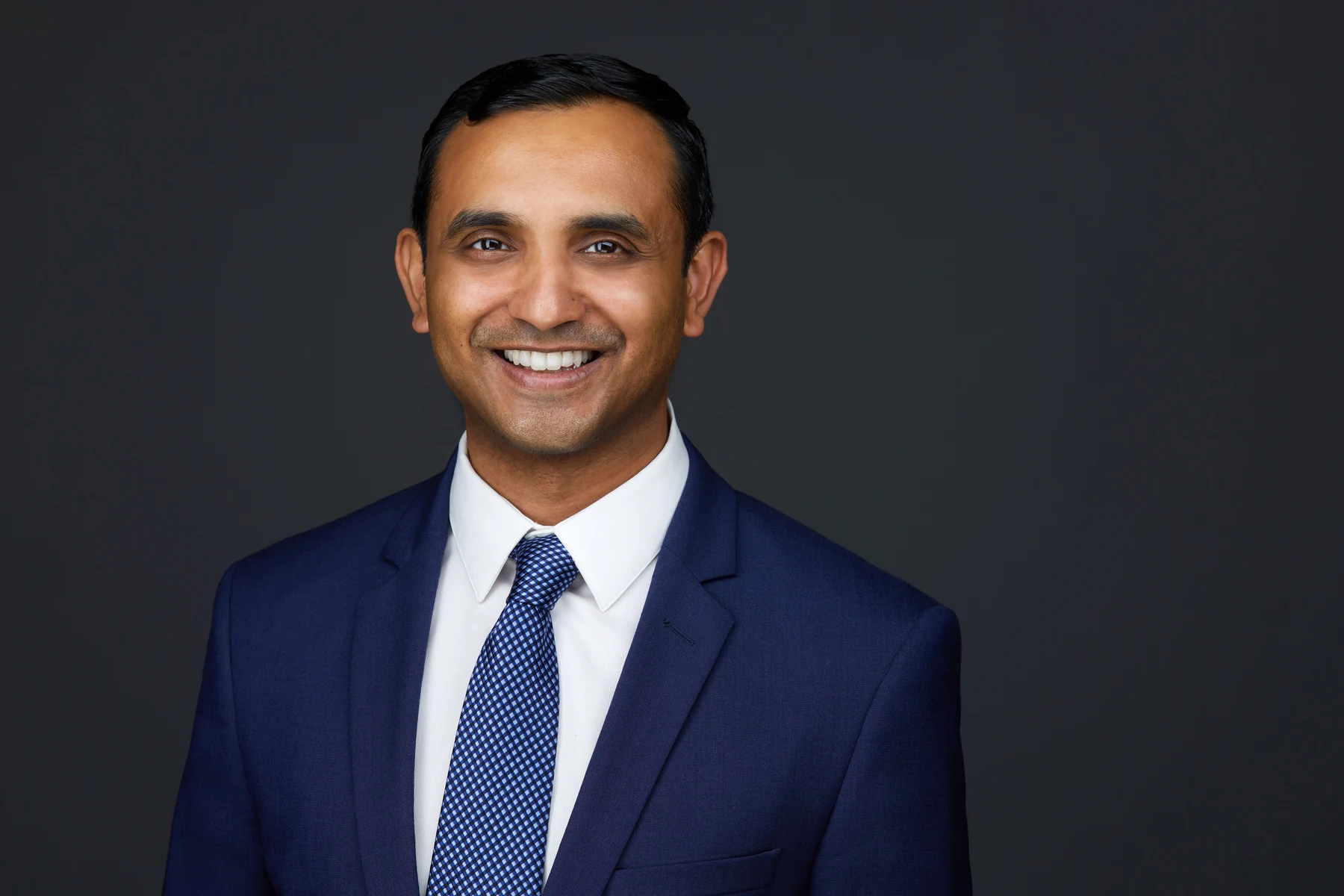 Shyam Ganesh in a navy suit and tie, Edmonton studio