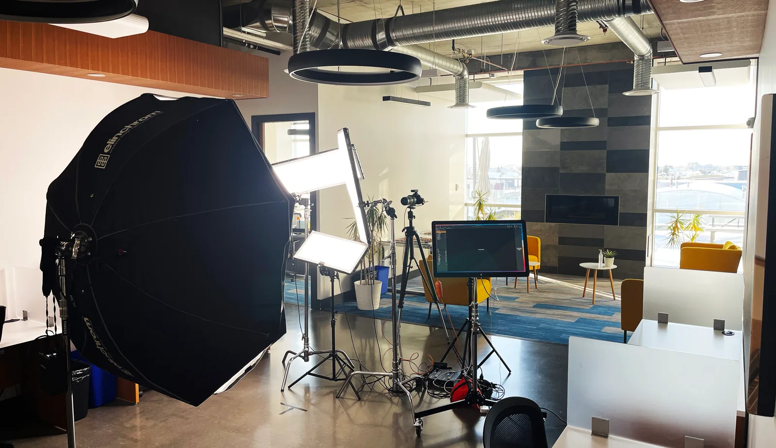 A full headshot setup — octabox, panels, camera and monitor — standing in the middle of a client’s open-plan office in Edmonton